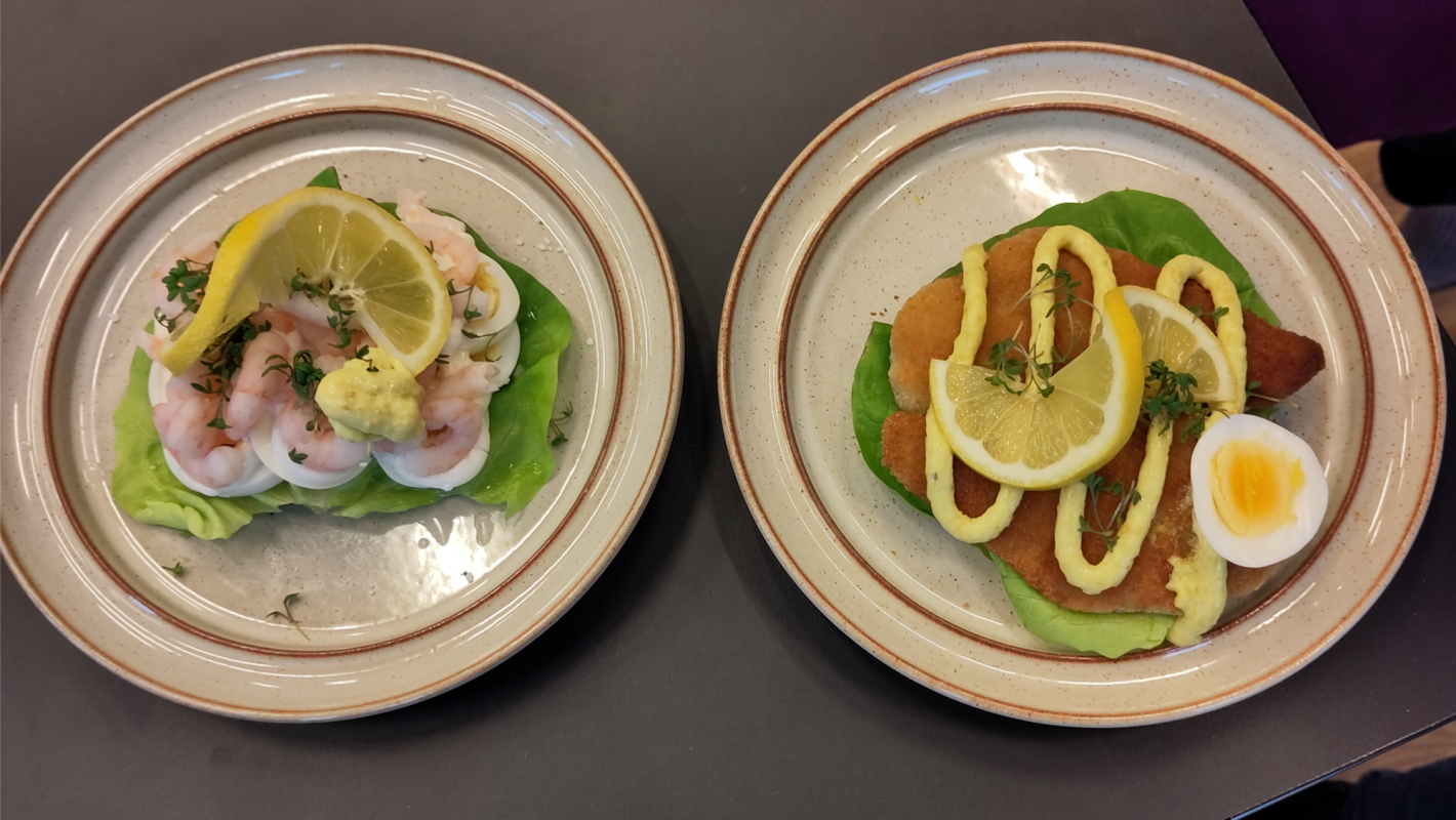 To stykker smørrebrød: Det ene med æg og rejer - det andet med fiskefileter og et halvt æg, som ligger ved siden af